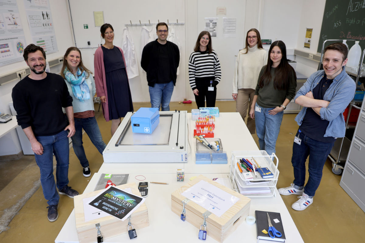 Acht Teammitglieder versammelt um einen Tisch mit Gegenständen aus dem Escape Room