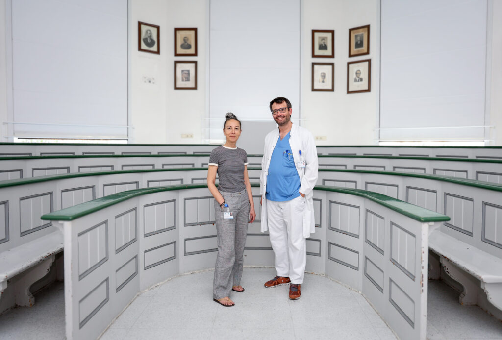 Die Forscher:innen Sandrine Dubrac und Stefan Blunder stehen in einem alten Hörsaal.
